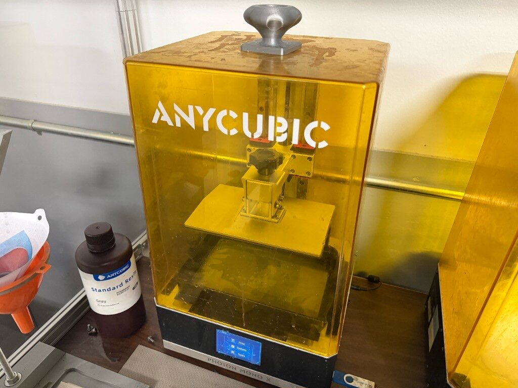 Anycubic Photon Mono X resin 3D printer on a workbench with gray resin and a filter funnel