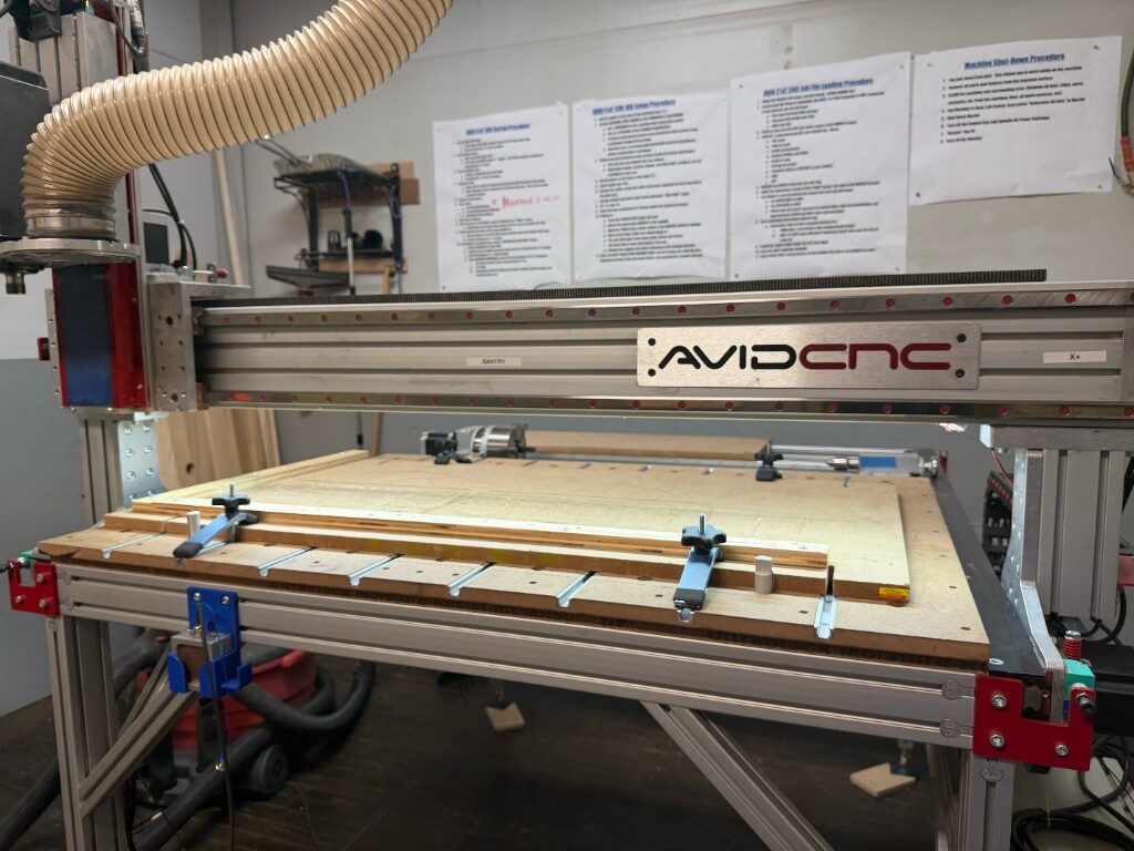 AVID CNC router with a wood sheet clamped to the bed in the shop
