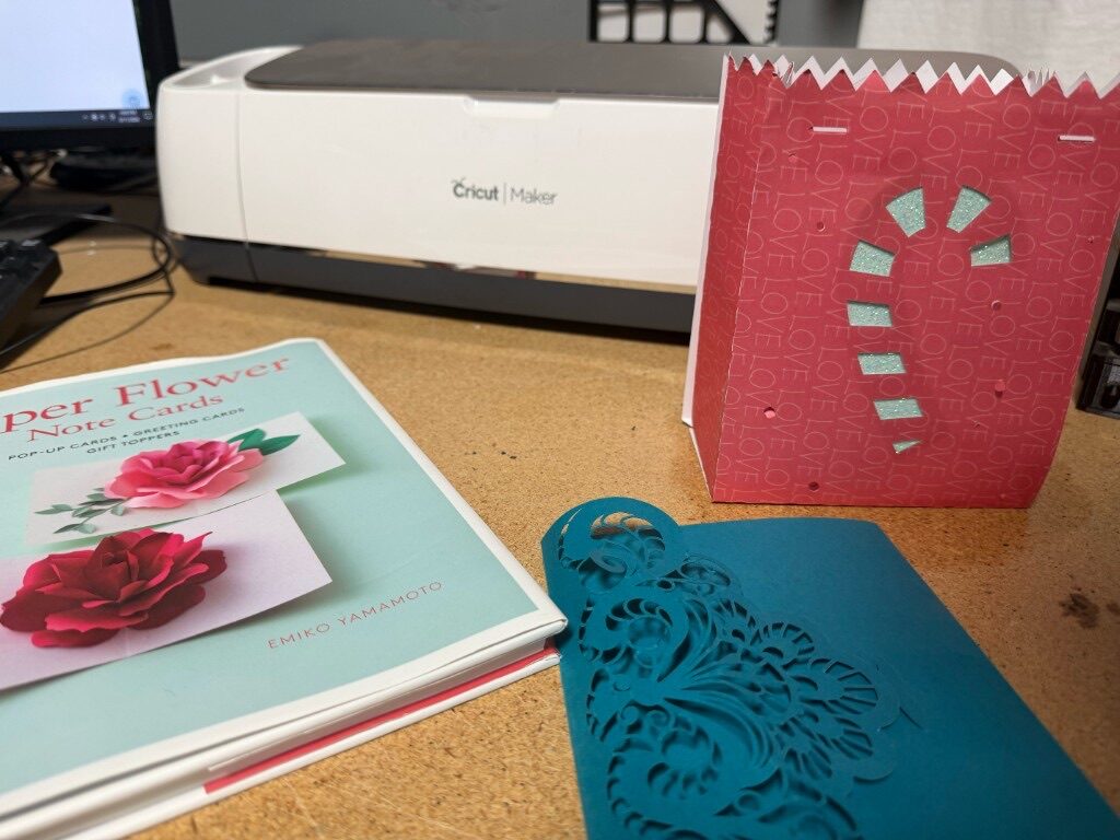 Cricut Maker on a desk with cut cardstock and a gift bag
