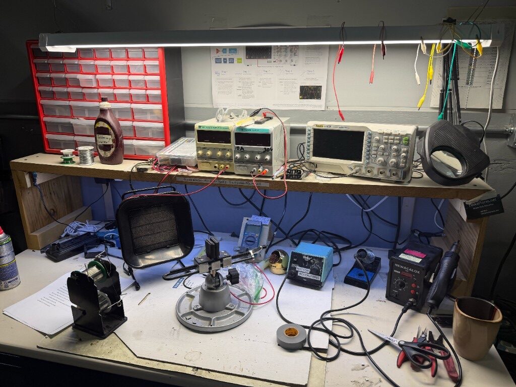Electronics workbench with soldering stations, oscilloscope, power supplies, and tools