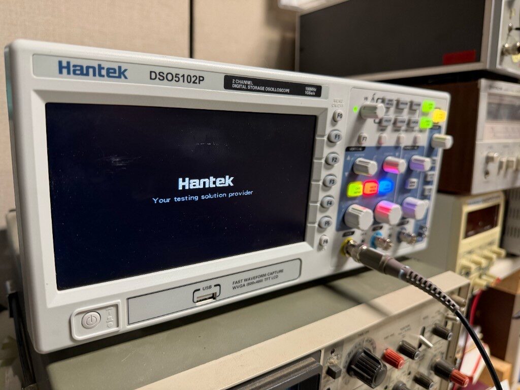 Hantek digital storage oscilloscope on the electronics bench with a probe connected