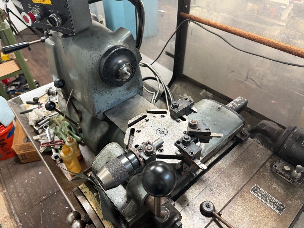 Metal lathe turret with drill chuck and cutting tools, emergency stop on the headstock