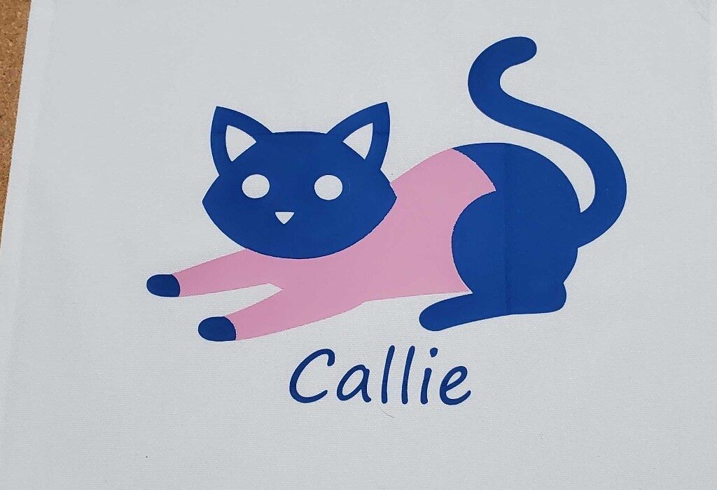 Navy and pink vinyl cat graphic labeled Callie on white fabric