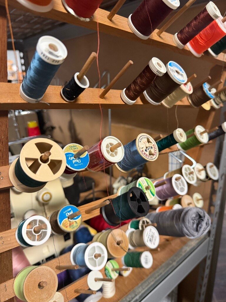 Wooden wall rack filled with colorful spools of sewing thread