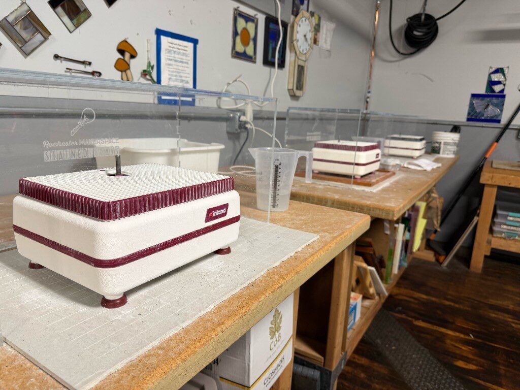Row of glass grinders on a stained glass workbench with Rochester Makerspace splash guards