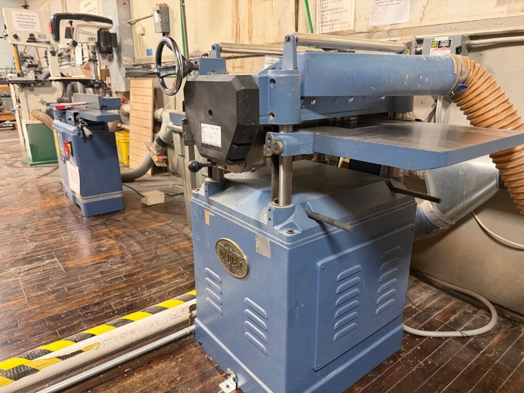 Blue Oliver thickness planer in the wood shop with dust collection hose attached