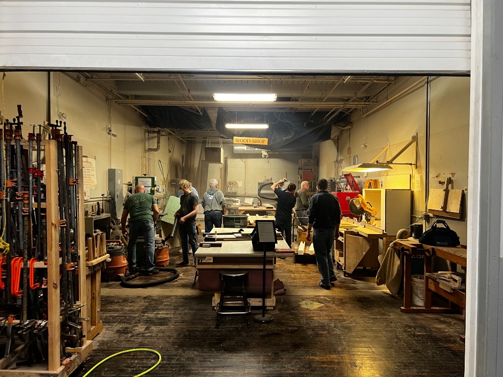 Several people working at benches and machines in the wood shop