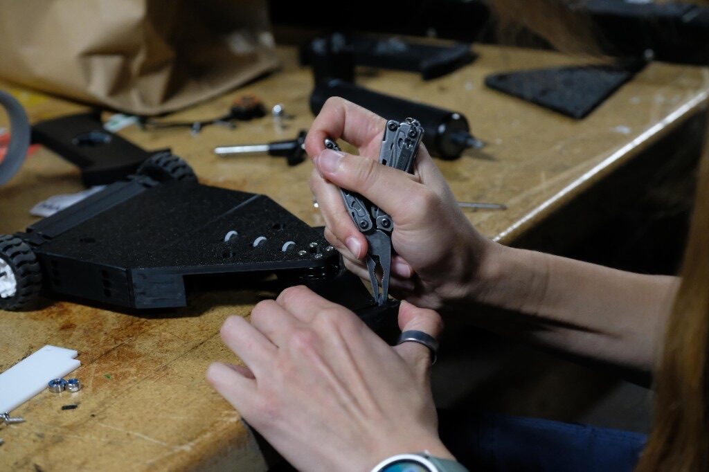 Hands assembling a small robot chassis